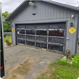 Black garage door on gray shingle building