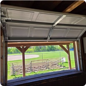 Open garage door interior view onto a field, new construction